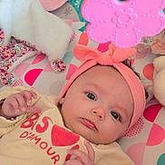 Céleste participe au concours pour gagner de l'argent avec cette photo : baby, infant, headband, toy, flower_toy, play_mat, colorful, pink, peach, cream_sweater, cute, child, indoors, soft_toys, hand, face, eyes, lying_down, closeup, adorable