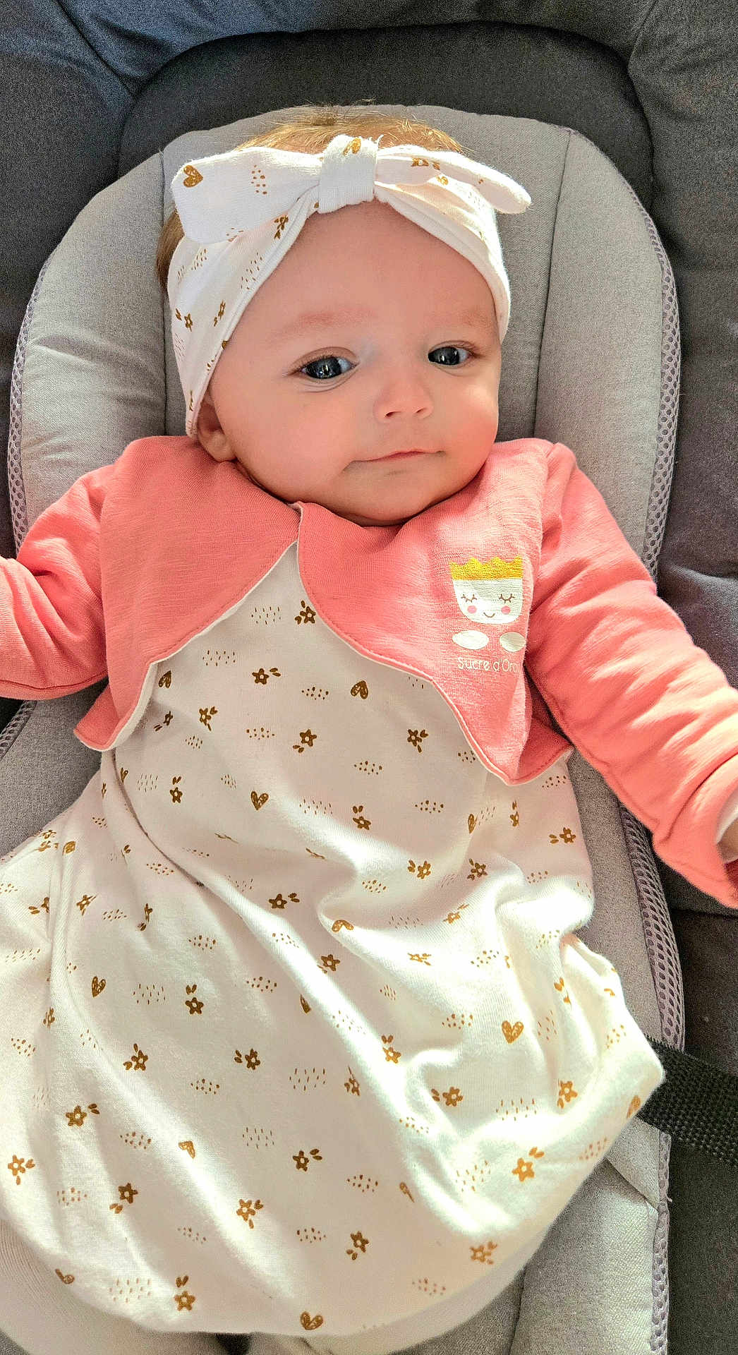 Céleste a rejoint le concours — aidez-le/la à gagner de superbes lots ! baby, infant, headband, pink_jacket, cushion, seat, clothing, pattern, face, eyes, skin, cute, child, portrait, indoors, soft_light, young_child, apparel, relaxing, adorable