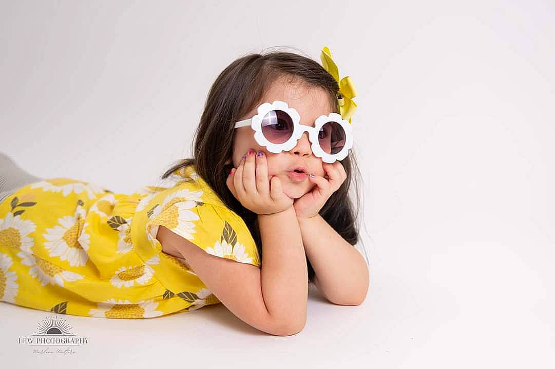 Angelica is registered to the contest to win money with this photo: baby_toddler_clothing, black_hair, comfort, cool, eyewear, facial_expression, flooring, fun, gesture, goggles, hairstyle, happy, mouth, neck, person, skin, sleeve, sunglasses, thigh, toddler