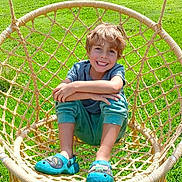 Gabin a rejoint le concours — aidez-le/la à gagner de superbes lots ! child, boy, smiling, swing, rope_swing, outdoor, grass, greenery, garden, casual_clothing, blue_shoes, happy, sunny, daylight, relaxing, seated, playful, nature, leisure, portrait