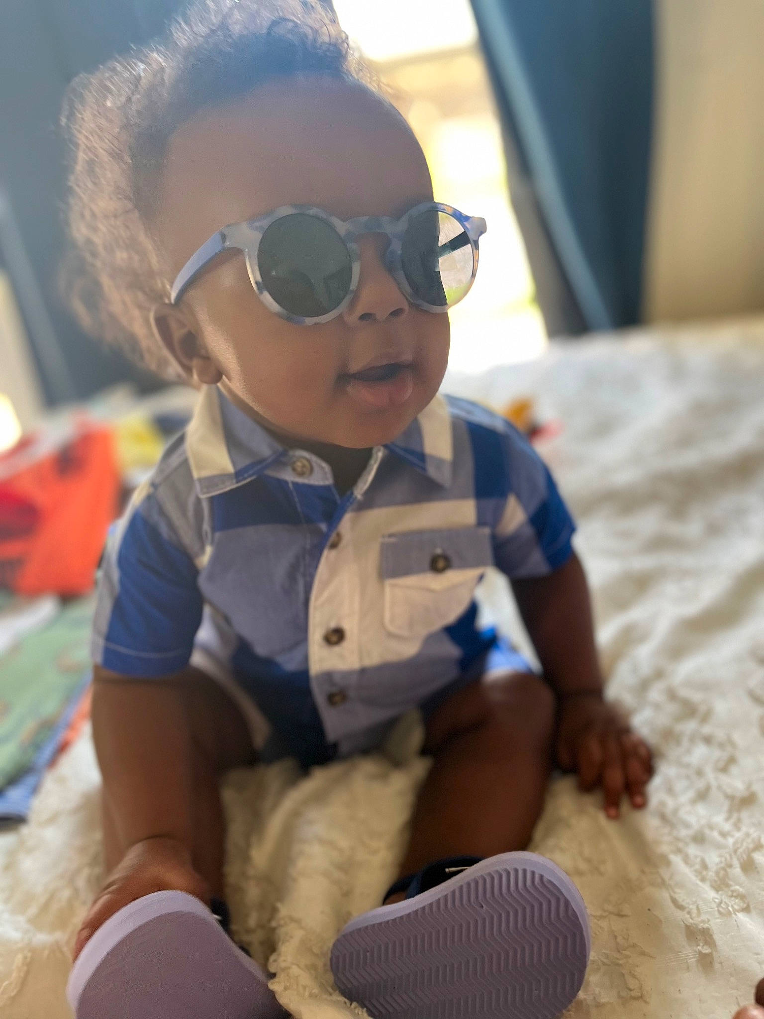 Moses is registered to the contest to win money with this photo: audio_equipment, child, doll, eye, eyewear, fun, glasses, goggles, happy, human_leg, person, personal_protective_equipment, sitting, skin, summer, sunglasses, thigh, toddler, toy, vacation