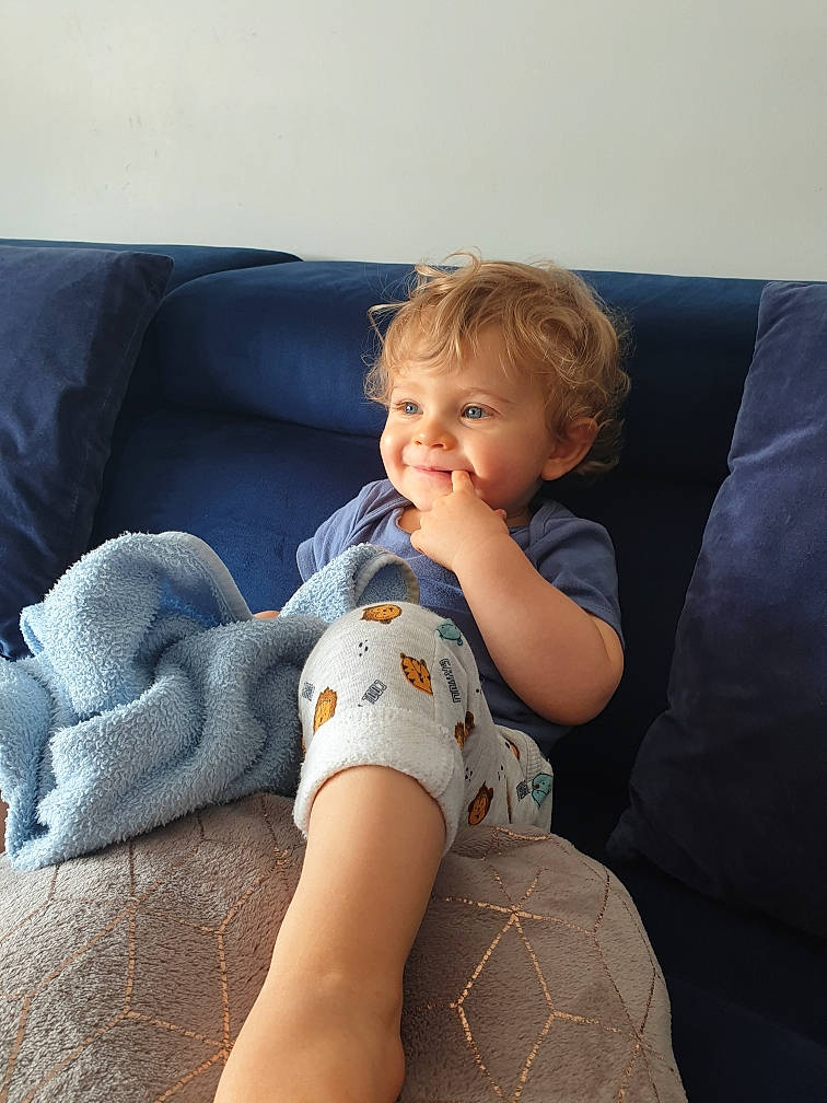 Milano participe au concours pour gagner de l'argent avec cette photo : arm, baby, baby_toddler_clothing, comfort, couch, elbow, finger, foot, human_body, human_leg, joint, knee, lap, leg, person, sitting, skin, smile, sock, thigh