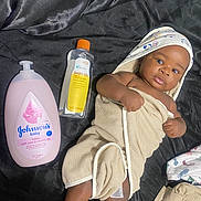 Jacquez is registered to the contest to win money with this photo: baby, towel, baby_lotion, baby_oil, infant, wrapped, cute, skin, face, head, lying_down, blanket, product_bottle, moisturizer, infant_care, baby_care, bedroom, fabric, hand, foot