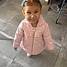child, girl, pink_jacket, smiling, standing, hair_clips, indoor, floor_tiles, shoes, clothing, happy, person, portrait, cute, young, casual, home, looking_up, small, toddler