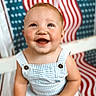 baby, child, smiling, romper, striped_clothing, sitting, happy, face, portrait, indoor, background_pattern, red, white, blue, cute, infant, person, bright, cheerful, playful