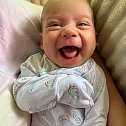 Keanu joined the competition — help win amazing prizes! baby, smiling, infant, onesie, rainbow, aloha, happy, cute, soft, plush, pillow, closeup, face, child, sleepwear, newborn, cheerful, person, comfort, indoors