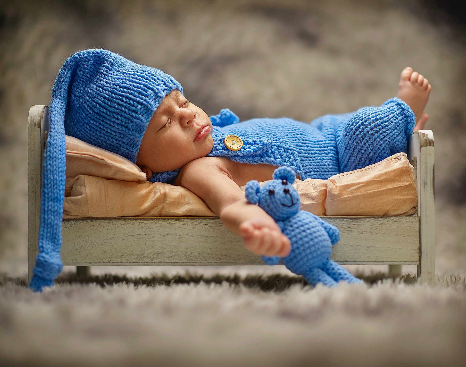 Keanu joined the competition — help win amazing prizes! baby, sleeping, knitted_hat, knitted_outfit, blue_clothing, teddy_bear, wooden_bed, pillow, carpet, soft_focus, portrait, infant, peaceful, cute, child, cozy, resting, indoor, blanket, toy