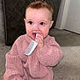 Indie is registered to the contest to win money with this photo: baby, child, indoor, carpet, sweater, pink, comb, toy, hair, pony_tail, cute, knitted, sitting, person, infant, face, hand, mouth, room, door