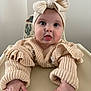 baby, infant, child, high_chair, knitted_clothing, headband, bow, sweater, hands, face, curious, indoor, cactus_pattern, soft_lighting, cute, portrait, skin, expression, young, person