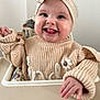 baby, child, high_chair, knitted_sweater, headband, bow, tongue_out, happy, smiling, indoors, cute, infant, person, face, hand, cozy, soft_lighting, close_up, seat, playful