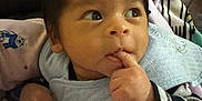 Anthony joined the competition — help win amazing prizes! baby, infant, child, finger_in_mouth, striped_clothing, penguin_patch, curly_hair, blanket, soft_lighting, candid, indoors, cute, portrait, looking_up, cozy, wearing_bib, hand_near_mouth, sleepwear, young_child, expressive_eyes