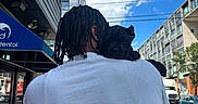 Sosa joined the competition — help win amazing prizes! person, dog, puppy, braided_hair, white_tshirt, shoulder, urban, street, building, blue_sky, clouds, sidewalk, car, truck, tree, daytime, relaxed, outdoor, power_lines, pet