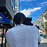 person, dog, puppy, braided_hair, white_tshirt, shoulder, urban, street, building, blue_sky, clouds, sidewalk, car, truck, tree, daytime, relaxed, outdoor, power_lines, pet