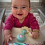 baby, bracelet, child, clothing, cute, expression, face, floor, furniture, hand, happy, high_chair, indoor, mirror, person, pink, play, smiling, toy, wood_floor