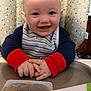 baby, high_chair, bib, baby_food, spoon, smiling, happy, infant, feeding_time, cushion, striped_clothing, food_container, cute, indoors, child, person, face, hands, table, playful