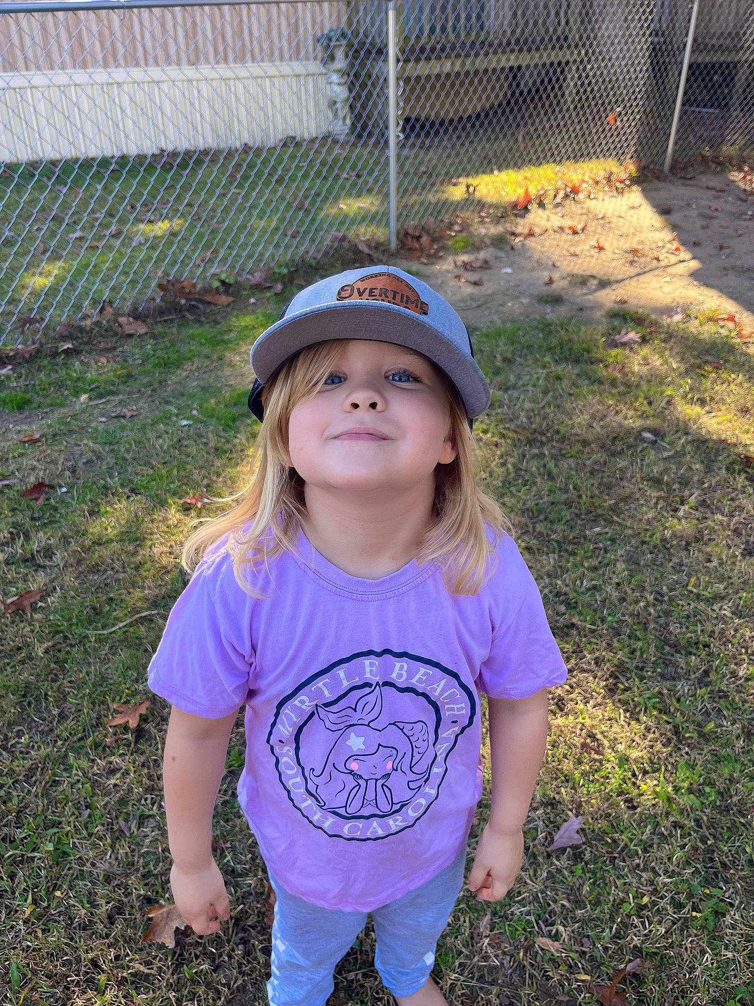 April is registered to the contest to win money with this photo: baby_toddler_clothing, baseball_cap, cap, child, clothing, electric_blue, fence, fun, grass, happy, hat, headwear, home_fencing, joy, mammal, mesh, people_in_nature, person, sleeve, t_shirt