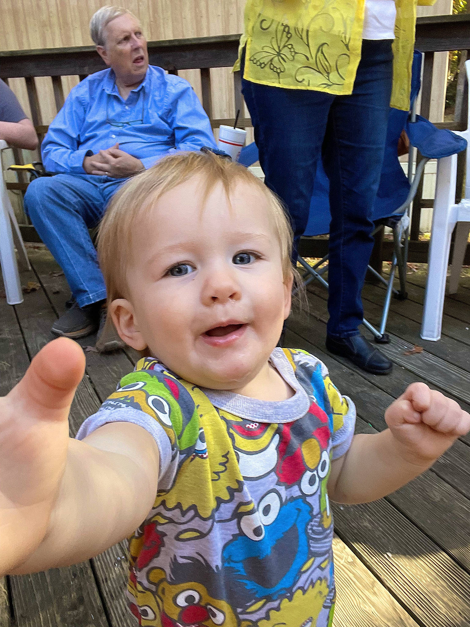 Ernest is registered to the contest to win money with this photo: baby, blue, chair, child, daytime, eye, fun, gesture, happy, human, iris, leisure, organ, people, person, skin, smile, standing, t_shirt, thumb