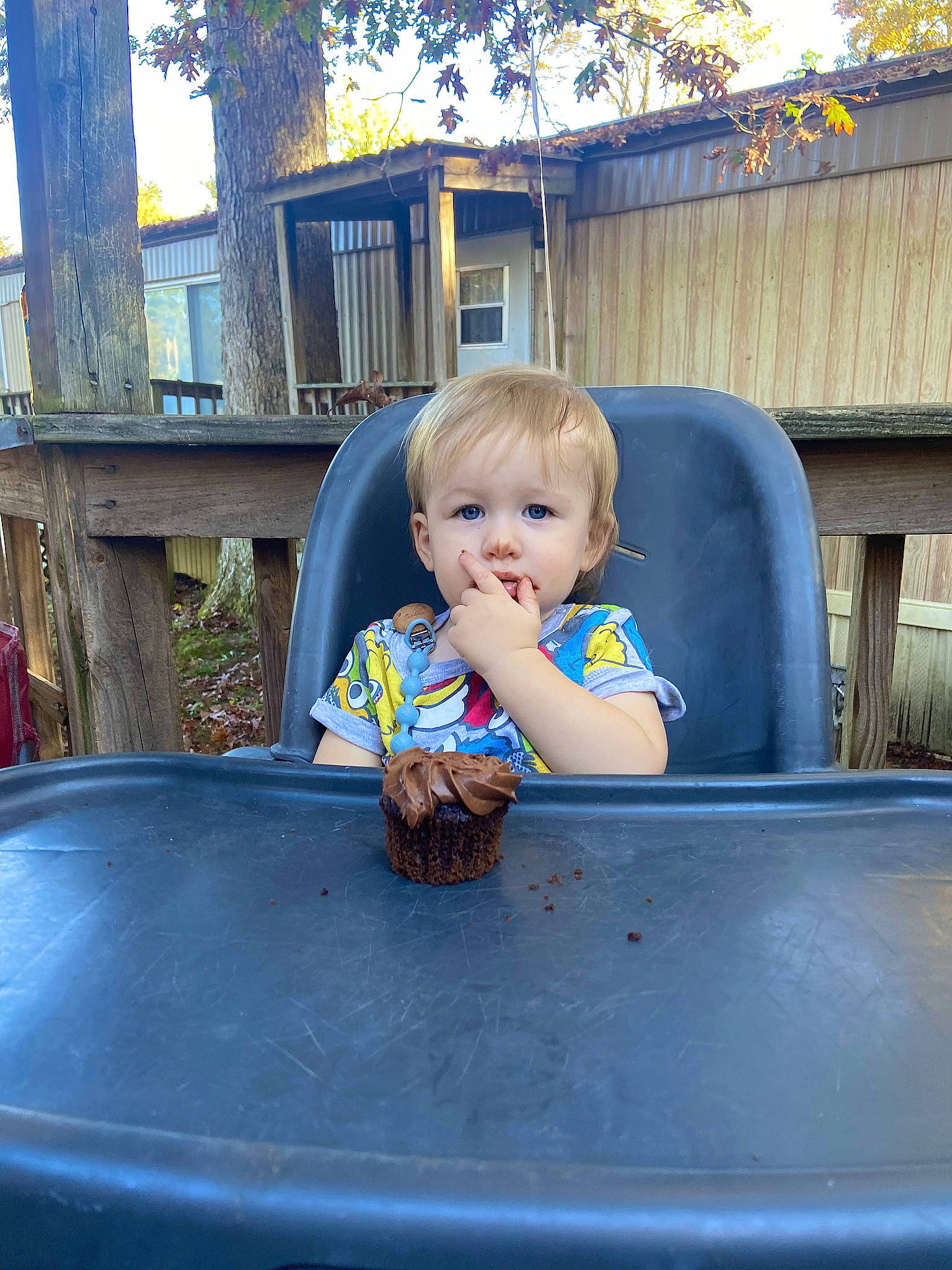 Ernest is registered to the contest to win money with this photo: baby, baby_toddler_clothing, child, city, daytime, facial_expression, fun, grass, hairstyle, leisure, person, plant, public_space, recreation, sitting, standing, t_shirt, table, toddler, tree