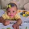 Marjeta joined the competition — help win amazing prizes! baby, child, yellow_clothing, butterfly_hair_clip, bed, blanket, plush_toy, face, hand, indoor, headboard, tufted, cute, infant, portrait, smiling, toddler, soft_toys, reaching_hand, cozy