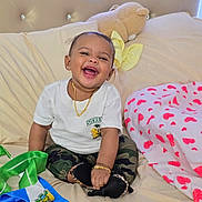 Marjeta joined the competition — help win amazing prizes! baby, smiling, sitting, bed, teddy_bear, white_tshirt, camo_pants, black_shoes, gold_jewelry, ribbons, blanket, heart_pattern, happy, child, indoor, portrait, cute, accessory, soft_toy, comfortable