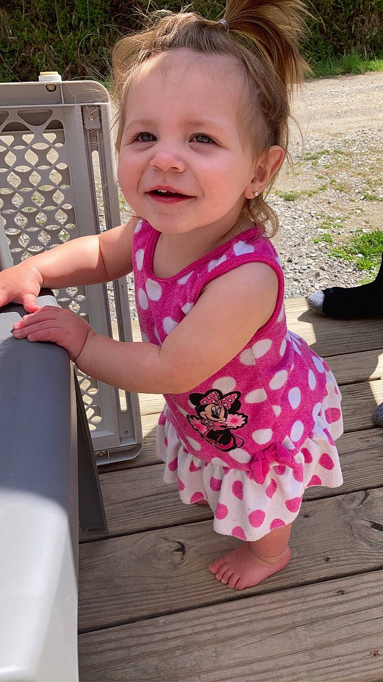 Vivien is registered to the contest to win money with this photo: arm, baby_toddler_clothing, cheek, dress, eye, face, facial_expression, gesture, hair, hairstyle, happy, head, human, joy, person, pink, shoulder, skin, sleeve, smile