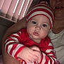 baby, child, person, red_clothing, striped_hat, striped_sleeves, indoor, window_blinds, arm, holding, face, blue_eyes, cheeks, casual, portrait, motion_blur, infant, candid, human, clothing