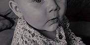 Aina participe au concours pour gagner de l'argent avec cette photo : baby, child, pigtails, curious, black_and_white, toy, indoor, sitting, closeup, face, expression, clothing, patterned_shirt, person, couch, home, portrait, cute, young, infant