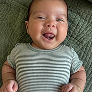 Romeo is registered to the contest to win money with this photo: baby, smiling, tongue_out, striped_clothing, bracelet, green_blanket, infant, cute, happy, closeup, portrait, child, skin, hand, face, lying_down, soft_light, young, one_piece, adorable