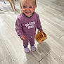toddler, child, smile, purple_clothing, basket, indoor, dog, floor_tiles, standing, happy, person, pet, canine, casual_wear, shoes, light_hair, small_basket, home, cute, playful