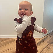 Paizley joined the competition — help win amazing prizes! toddler, child, smiling, indoor, dress, maroon, turkey_embroidery, white_shirt, long_sleeves, wooden_floor, standing, happy, cute, baby, person, playful, flooring, wall, home, portrait