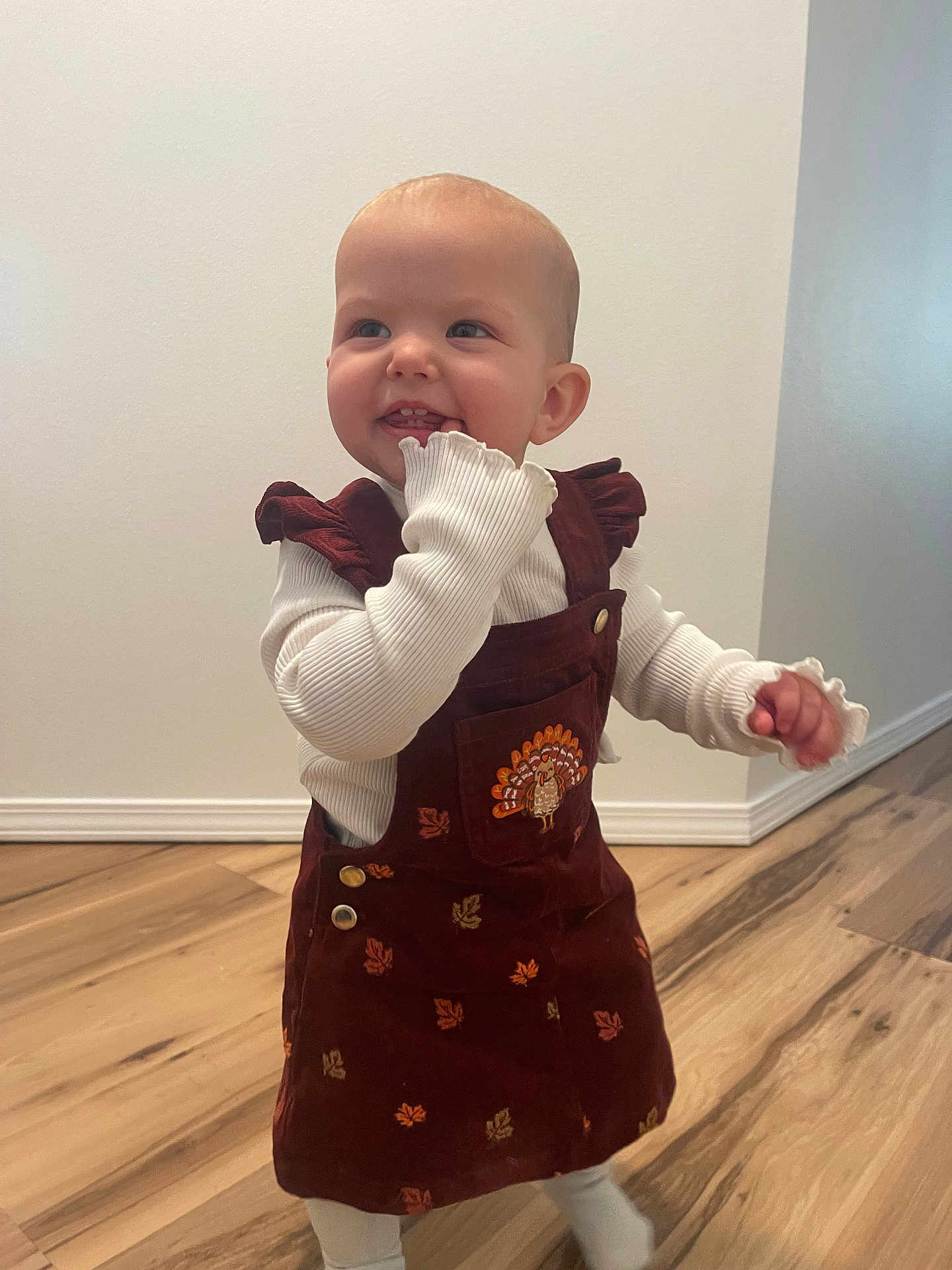 Paizley joined the competition — help win amazing prizes! toddler, child, smiling, indoor, dress, maroon, turkey_embroidery, white_shirt, long_sleeves, wooden_floor, standing, happy, cute, baby, person, playful, flooring, wall, home, portrait