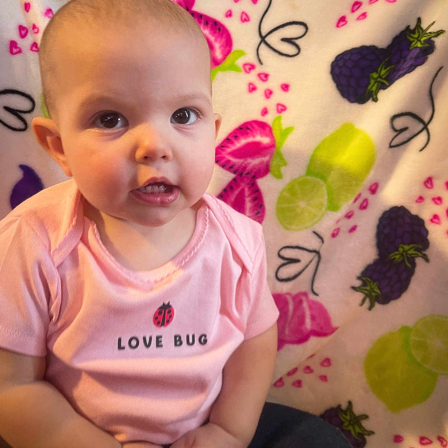 Paizley is registered to the contest to win money with this photo: baby, blackberry, blanket, child, clothing, cute, expression, face, fruit_pattern, hands, indoor, infant, lime, love_bug, person, pink_shirt, portrait, sitting, strawberry, young