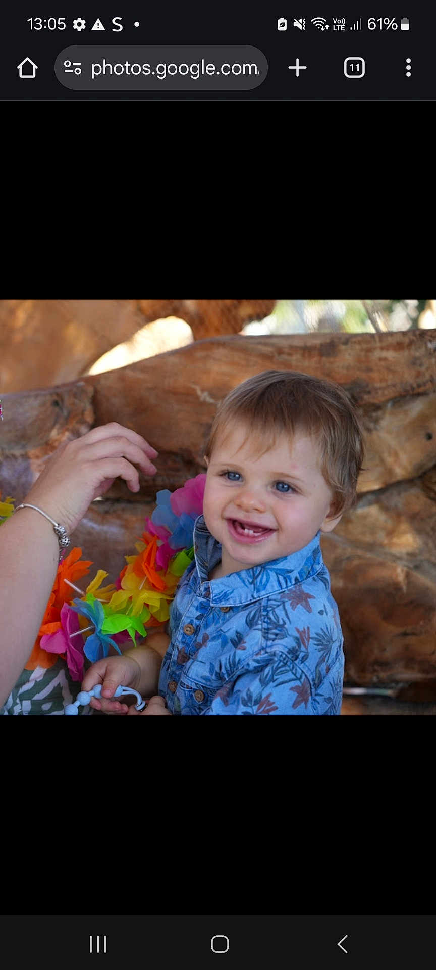 Ezio participe au concours pour gagner de l'argent avec cette photo : toddler, child, smiling, blue_eyes, blue_shirt, floral_pattern, beads, hand, bracelet, lei, colorful, wood_background, happy, cute, portrait, indoors, playful, baby, person, closeup
