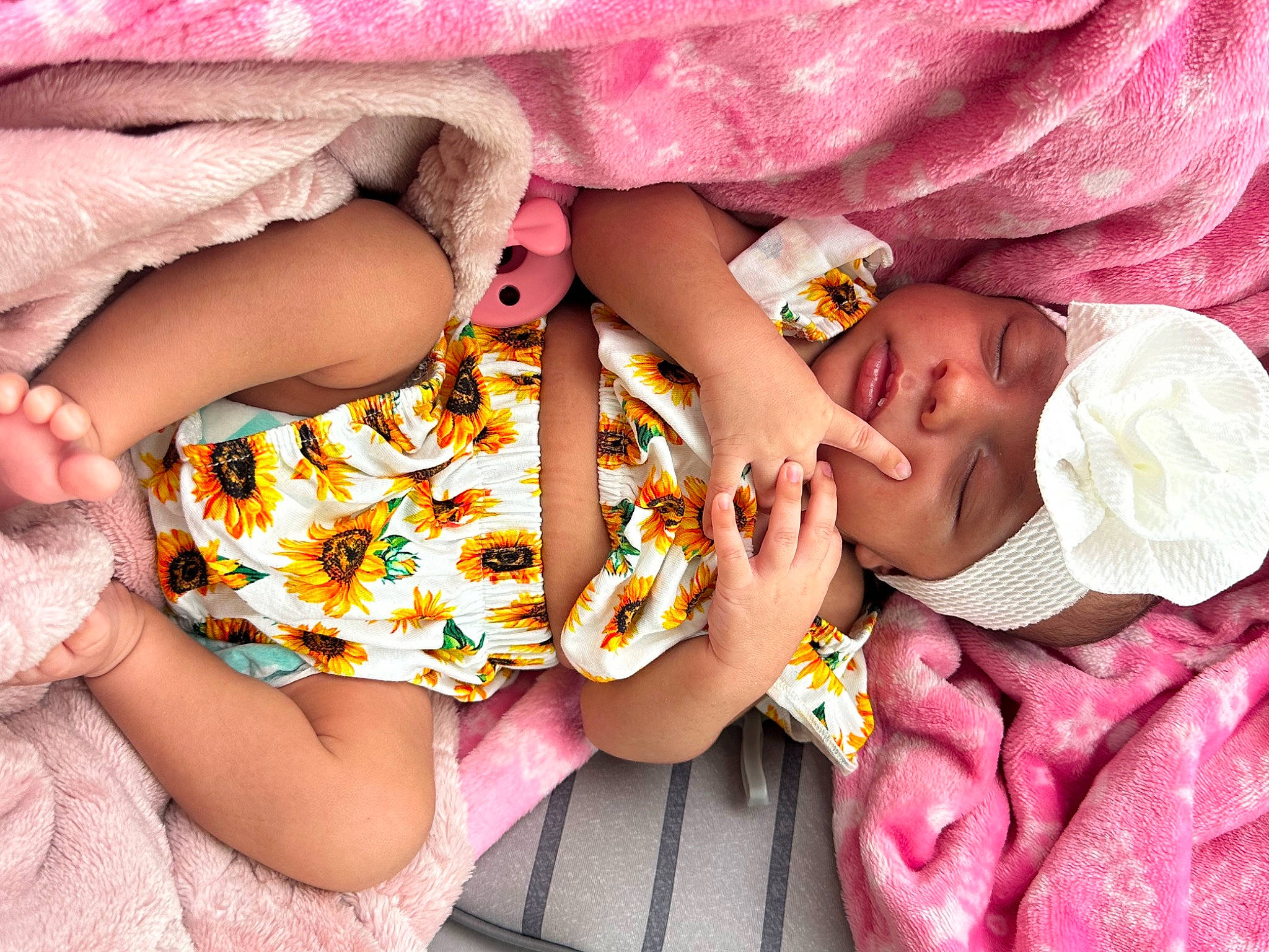 Alaysia is registered to the contest to win money with this photo: arm, baby, baby_toddler_clothing, child, comfort, dress, finger, hand, headwear, human_body, leg, nail, pattern, person, pink, purple, skin, sleeve, textile, thigh