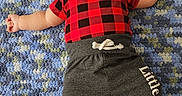 Jace joined the competition — help win amazing prizes! baby, infant, child, lying_down, red_shirt, checkered_pattern, grey_pants, barefoot, carpet, blue_carpet, textile, wooden_sign, four_months, smiling, cute, indoors, portrait, person, young_child, cozy