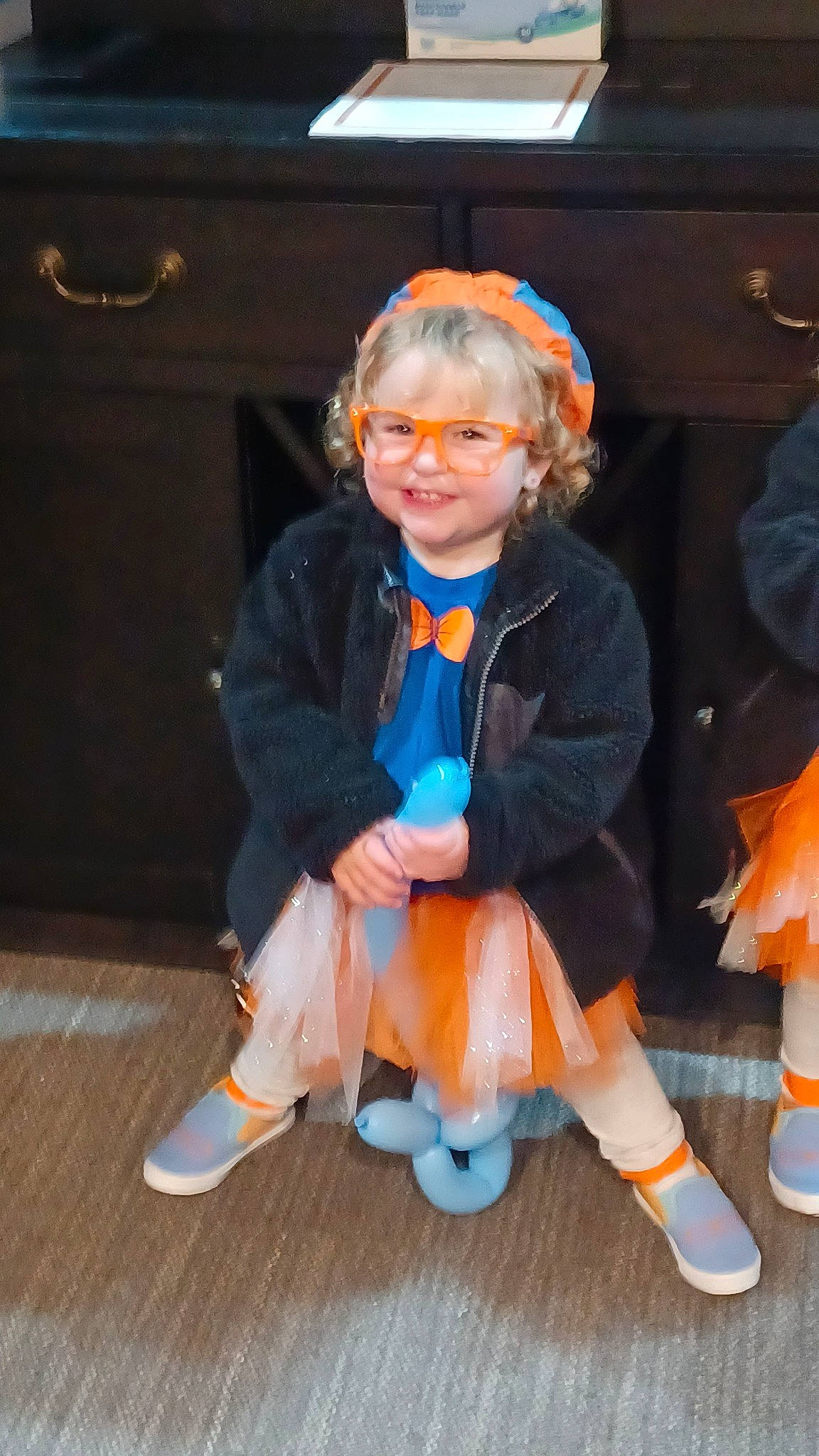 Evie joined the competition — help win amazing prizes! child, costume, electric_blue, event, eyewear, flooring, fun, fur, hat, joy, lap, orange, person, room, shoe, sitting, smile, sock, toddler, toy