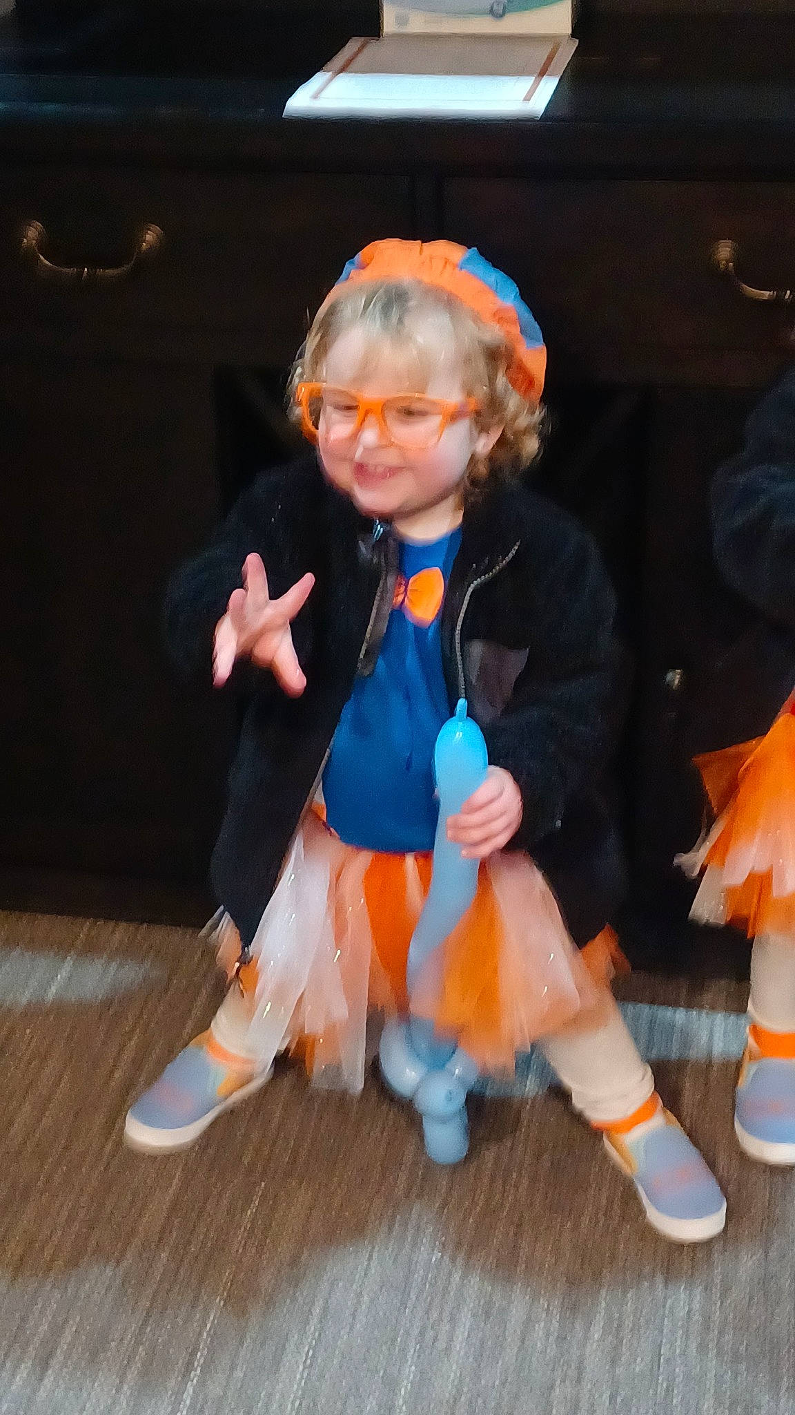 Evie is registered to the contest to win money with this photo: child, costume, electric_blue, entertainment, event, face, flooring, hardwood, hat, human_leg, joy, orange, performing_arts, person, smile, sock, tail, toddler, toy, wig