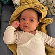 Leo participe au concours pour gagner de l'argent avec cette photo : baby, infant, towel, yellow_towel, onesie, white_clothing, face, eyes, hand, blanket, soft, cute, curious, lying_down, indoors, child, portrait, head, expression, fabric