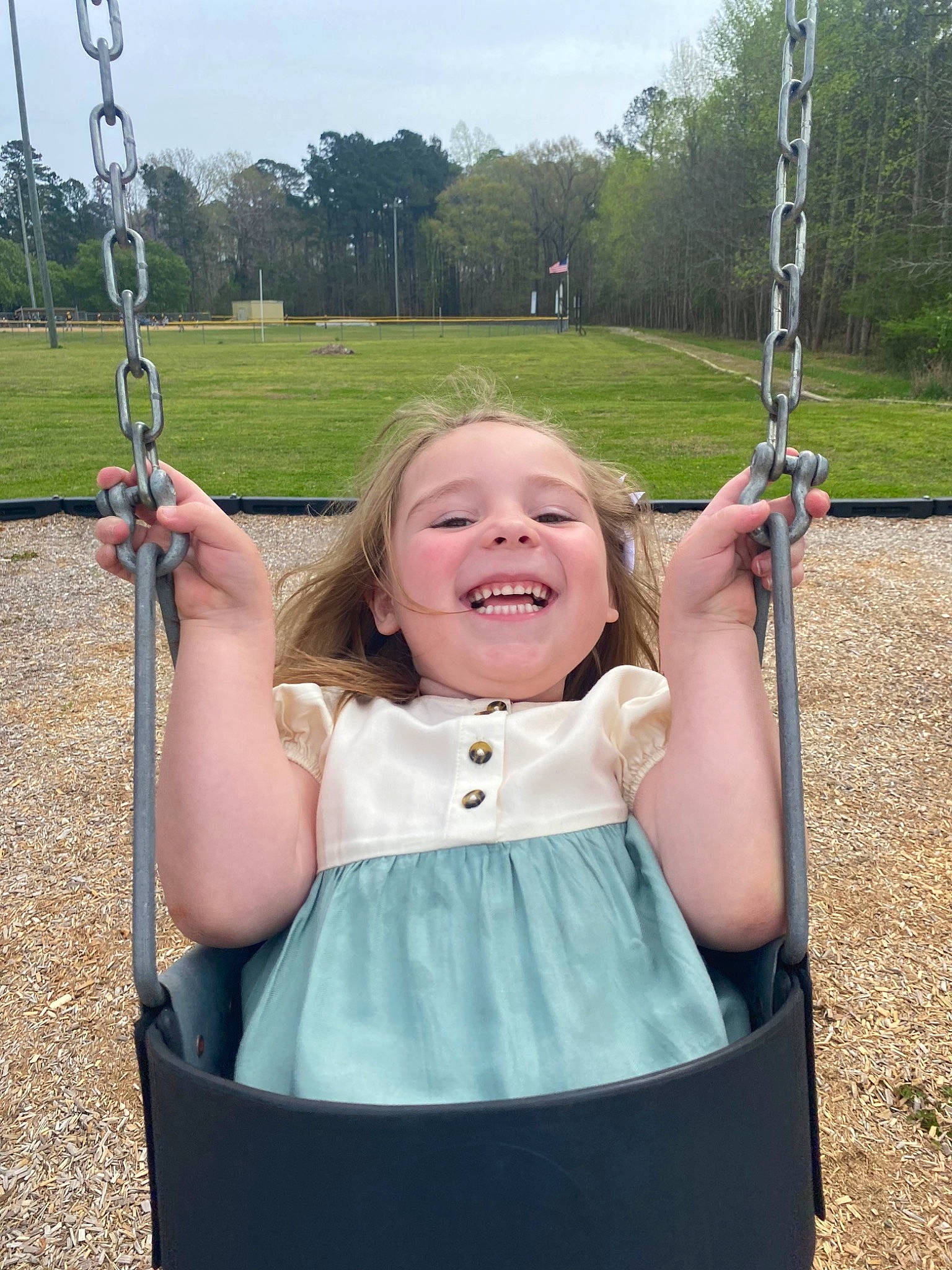 Annalynn is registered to the contest to win money with this photo: arm, clothing, dress, eye, face, facial_expression, green, hair, hand, head, human_body, joy, natural_environment, nature, person, plant, sky, smile, swing, tree