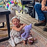 baby, child, dress, feet, furniture, grill, happy, headband, legs, nature, outdoor, person, playtime, rocking_horse, rug, smiling, stuffed_animal, toy, unicorn, wooden_deck