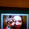 Snugglebears is registered to the contest to win money with this photo: woman, person, dog, canine, pet, portrait, selfie, close_up, face, smiling, indoor, screen, monitor, photograph, low_resolution, pixelated, orange_lighting, dark, companion, home