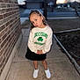 Dalaya is registered to the contest to win money with this photo: child, girl, standing, pose, playful, sweatshirt, black_skirt, white_shoes, sidewalk, brick_wall, outdoor, evening, suburban, puckered_lips, casual_clothing, long_hair, person, smile, cute, young