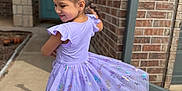 Dalaya is registered to the contest to win money with this photo: child, girl, dress, purple, butterfly, braids, hair, smile, sidewalk, shadow, brick_wall, door, outdoor, sunlight, sneakers, concrete, playful, twirling, happy, casual