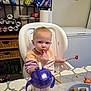 toddler, high_chair, food, fries, fork, strawberry, sippy_cup, table, plate, kitchen, snacks, pantry, drink, plastic_container, baby, eating, child, indoor, person, casual