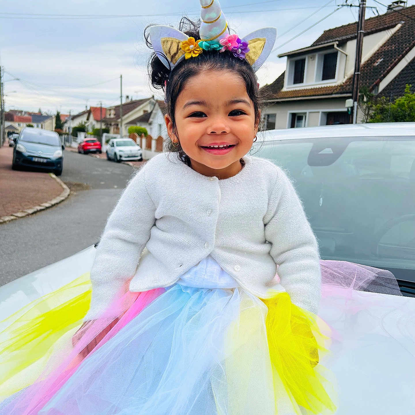 Rubby a rejoint le concours — aidez-le/la à gagner de superbes lots ! car, child, colorful, costume, cute, daylight, fashion, fun, girl, happy, headwear, outdoor, playful, portrait, residential_area, smiling, street, tutu, unicorn_headband, white_cardigan