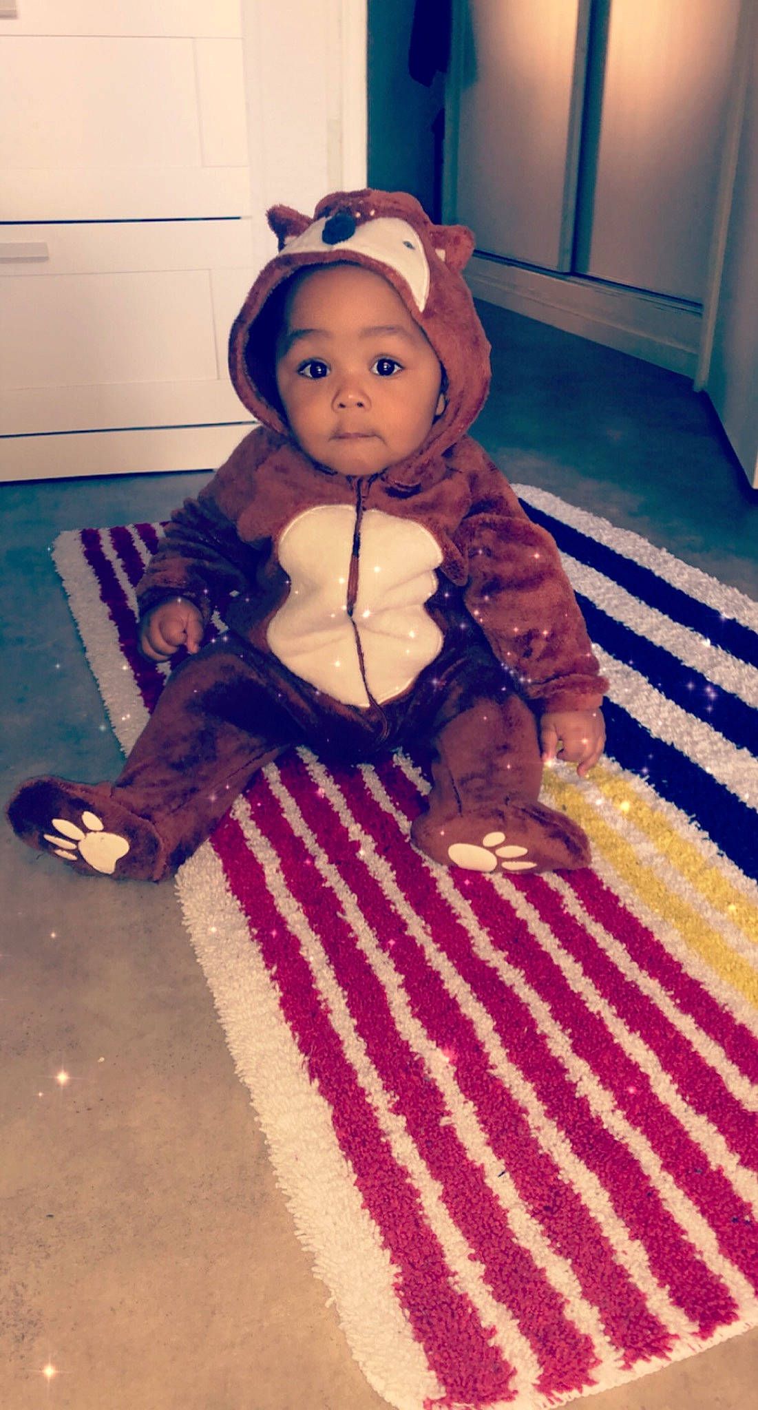 Maylon a rejoint le concours — aidez-le/la à gagner de superbes lots ! baby, baby_products, baby_toddler_clothing, brown, carpet, child, floor, flooring, headwear, mammal, mat, person, rug, textile, toddler, toy