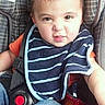 toddler, child, car_seat, bib, striped_bib, orange_shirt, jeans, seatbelt, face, expression, hair, indoor, sitting, person, clothing, baby, cute, funny_face, seat, car_interior