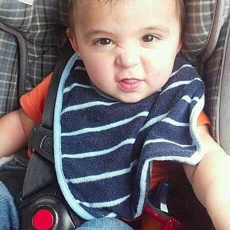 Carson joined the competition — help win amazing prizes! toddler, child, car_seat, bib, striped_bib, orange_shirt, jeans, seatbelt, face, expression, hair, indoor, sitting, person, clothing, baby, cute, funny_face, seat, car_interior
