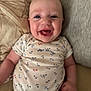anchor_pattern, apparel, baby, child, closeup, couch, cute, expression, face, happy, indoors, infant, joy, lying_down, onesie, person, pillow, skin, smiling, young