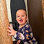 Hayson is registered to the contest to win money with this photo: toddler, child, pajamas, indoor, wood, hand, smiling, happy, face, person, clothing, home, iron_board, brown, background, cute, playful, young, standing, expression